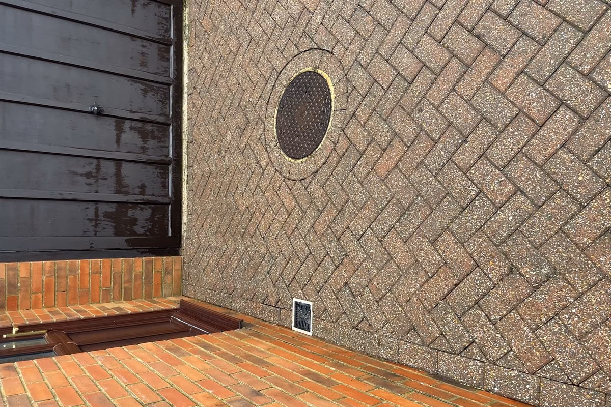 The cleaned courtyard from the far corner, showing the red brick border and the drain cover clear of growth
