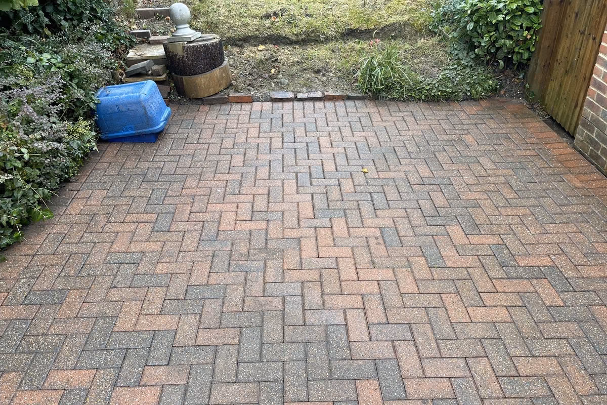 The same block paving driveway after jet washing and re-sanding, the original red and charcoal colour visible and the herringbone pattern clear again