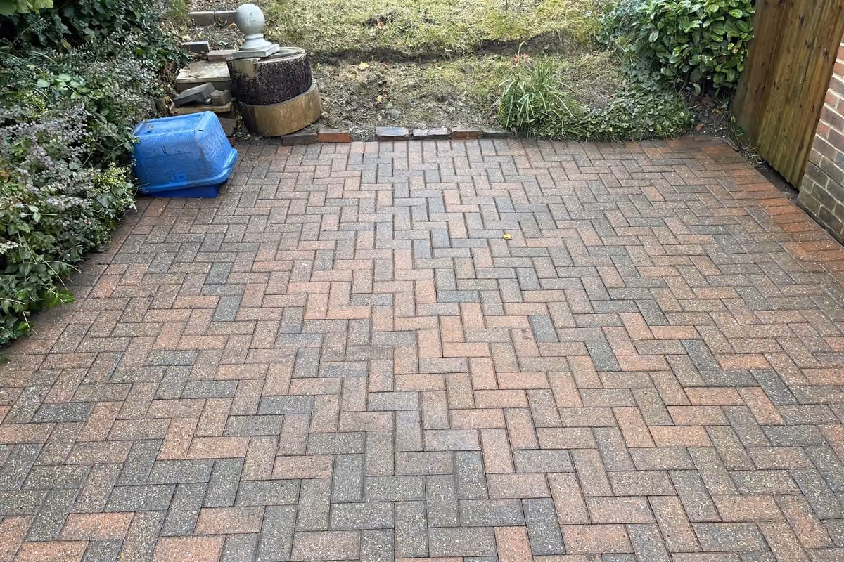 The same block paving driveway after jet washing and re-sanding, the original red and charcoal colour visible and the herringbone pattern clear again