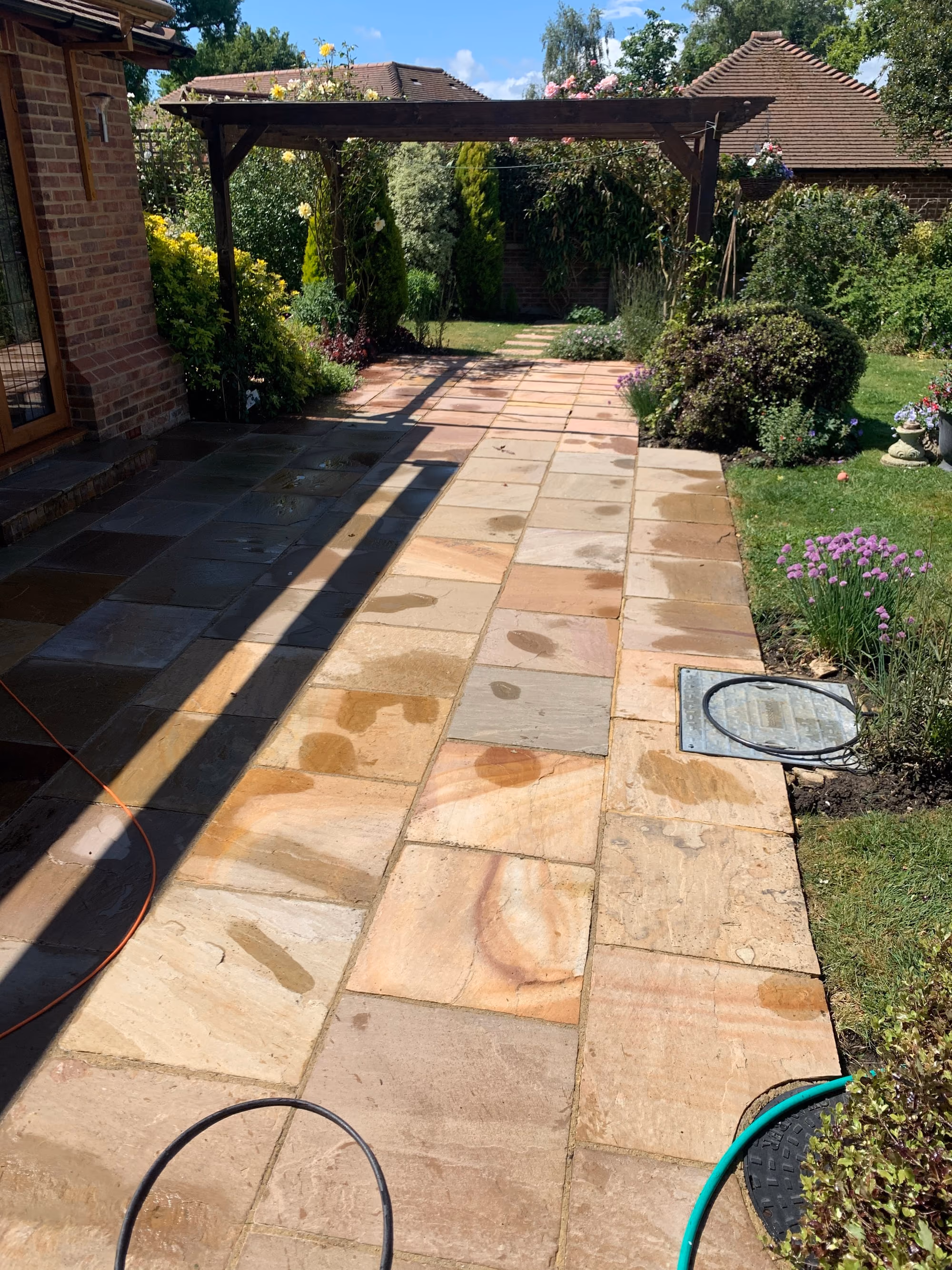 A freshly washed sandstone path still wet, the rust and ochre markings in the stone showing strongly, running between planted borders